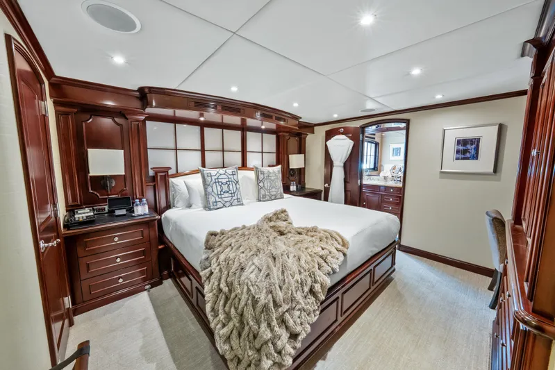 Nicole Evelyn Yacht Photos Pics Luxurious bedroom on 2005 Trinity Yachts Tri-Deck with elegant wood furnishings and plush bedding.