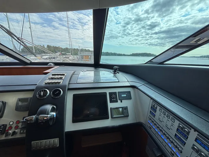 Schatzi Yacht Photos Pics Cockpit view of 2013 Fairline Squadron 78 Custom yacht with control panels and scenic water backdrop.