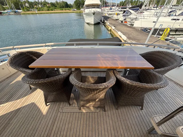 Schatzi Yacht Photos Pics Outdoor dining area on 2013 Fairline Squadron 78 Custom yacht, featuring wicker chairs and wooden table.