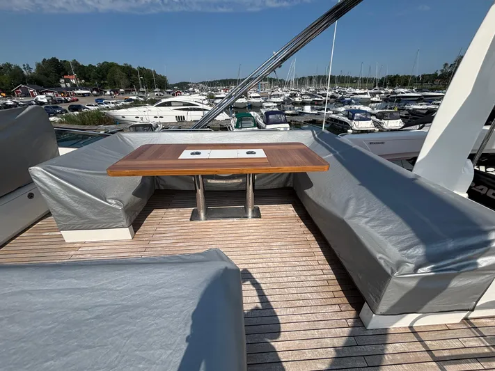 Schatzi Yacht Photos Pics Outdoor seating area on 2013 Fairline Squadron 78 Custom yacht, with covered benches and wooden table.