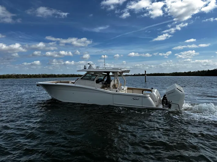  Yacht Photos Pics 2025 Scout 400 LXF boat cruising on open water under a partly cloudy sky.