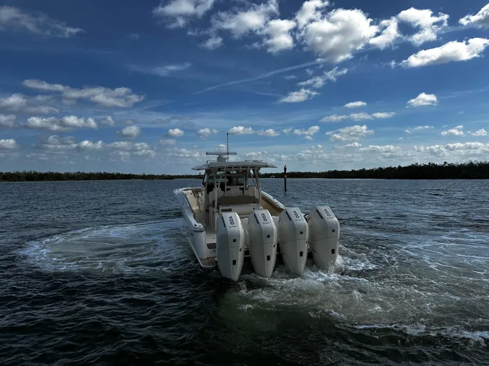  Yacht Photos Pics 2025 Scout 400 LXF boat with four engines cruising on open water under a cloudy sky.