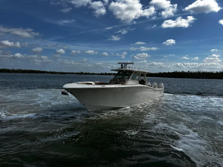  Yacht Photos Pics 2025 Scout 400 LXF boat cruising on open water under a partly cloudy sky.