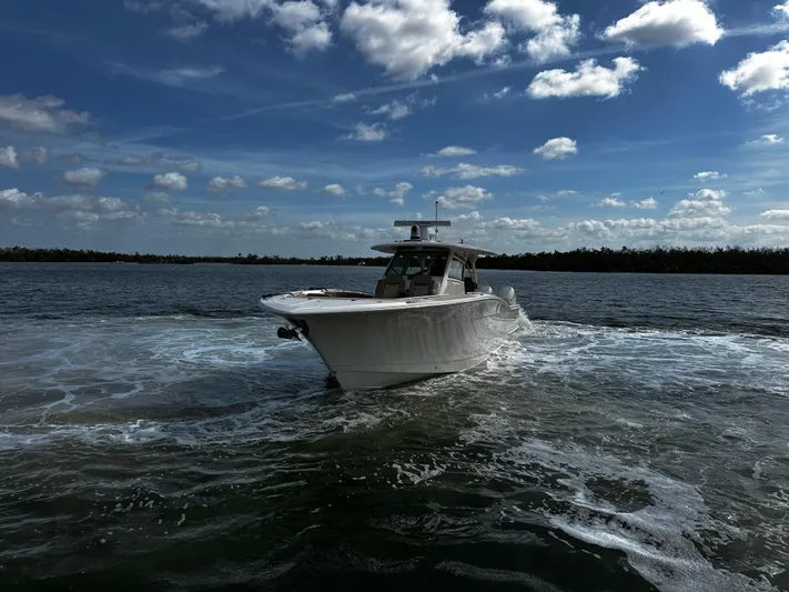  Yacht Photos Pics 2025 Scout 400 LXF boat cruising on open water under a partly cloudy sky.