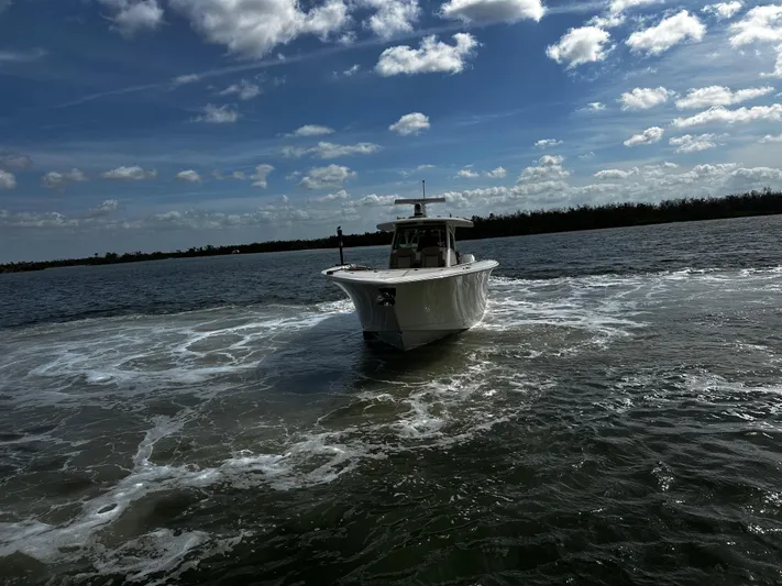  Yacht Photos Pics 2025 Scout 400 LXF boat cruising on a sunny day with blue skies and clouds.
