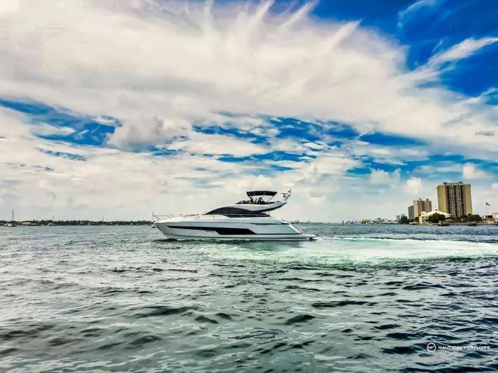  Yacht Photos Pics 2023 Fairline Phantom 65 yacht cruising on a sunny day with city skyline in the background.