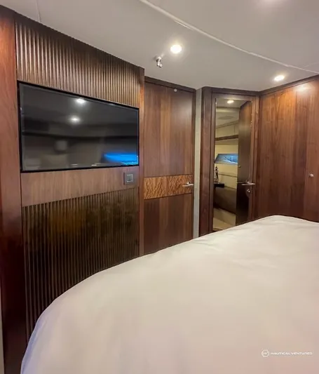  Yacht Photos Pics Luxurious bedroom interior of 2023 Fairline Phantom 65 yacht with wood paneling and flat-screen TV.