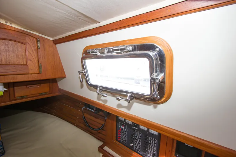 Equanimity Yacht Photos Pics Interior of 1992 Pacific Seacraft Cutter, featuring a porthole and wooden cabinetry.