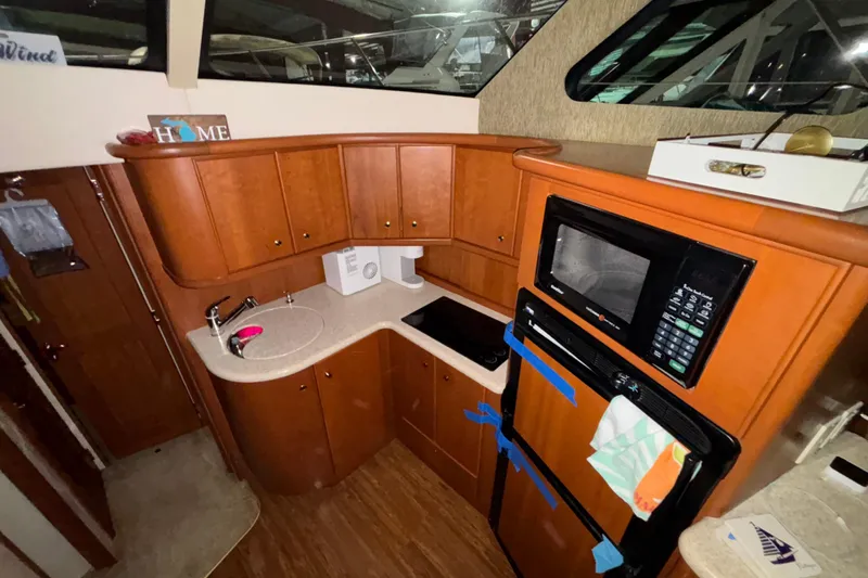  Yacht Photos Pics 2005 Silverton 34 Convertible yacht kitchen with wood cabinetry, microwave, and compact appliances.