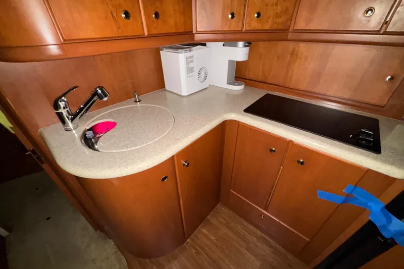  Yacht Photos Pics 2005 Silverton 34 Convertible yacht kitchen with sink, stovetop, and wooden cabinetry.