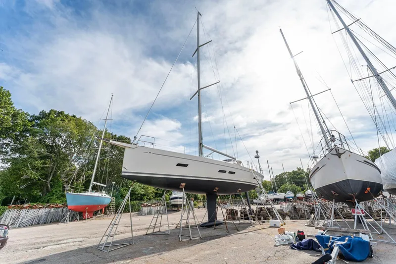 Rusalka Yacht Photos Pics Italia Yachts 13.98, 2015 model, on dry dock with other sailboats under a cloudy sky.