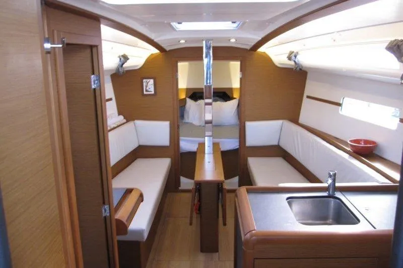 Naia Grey Yacht Photos Pics Interior of 2022 Jeanneau Sun Odyssey 349 sailboat, featuring cozy seating and compact kitchen area.