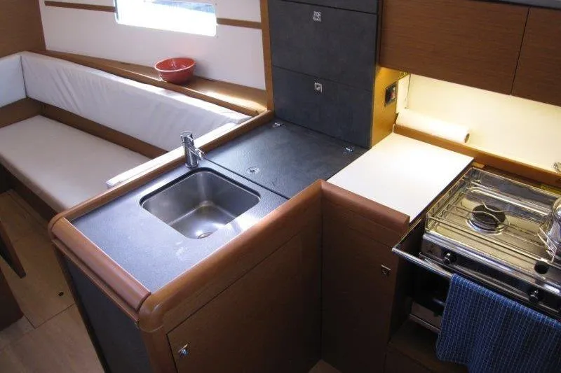 Naia Grey Yacht Photos Pics Interior of 2022 Jeanneau Sun Odyssey 349 yacht, featuring a compact kitchen with sink and stove.
