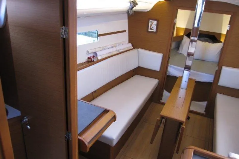 Naia Grey Yacht Photos Pics Interior of 2022 Jeanneau Sun Odyssey 349 sailboat, featuring cozy seating and wooden finishes.