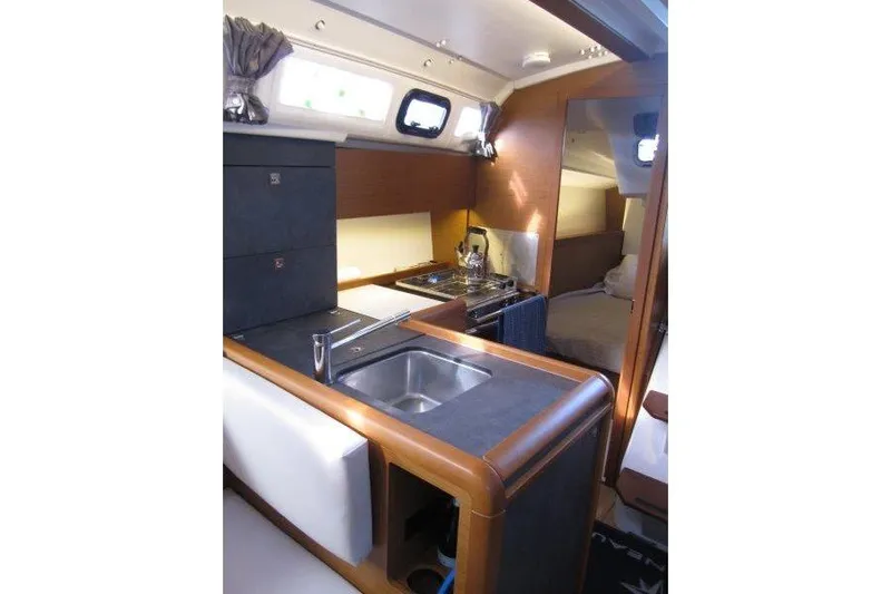 Naia Grey Yacht Photos Pics Interior of 2022 Jeanneau Sun Odyssey 349 yacht, featuring a compact kitchen and cozy cabin.