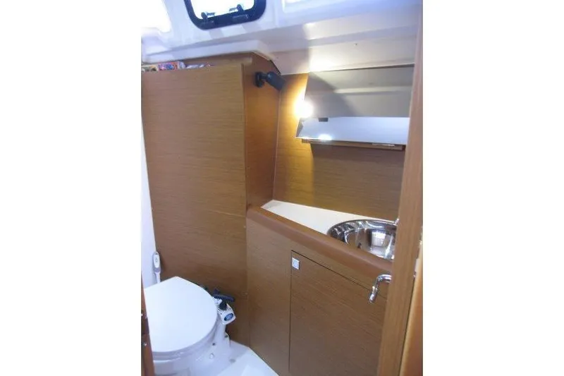 Naia Grey Yacht Photos Pics 2022 Jeanneau Sun Odyssey 349 yacht bathroom with wooden cabinetry and stainless steel sink.