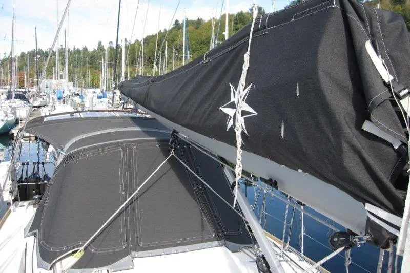 Naia Grey Yacht Photos Pics 2022 Jeanneau Sun Odyssey 349 sailboat with black sail cover in marina.