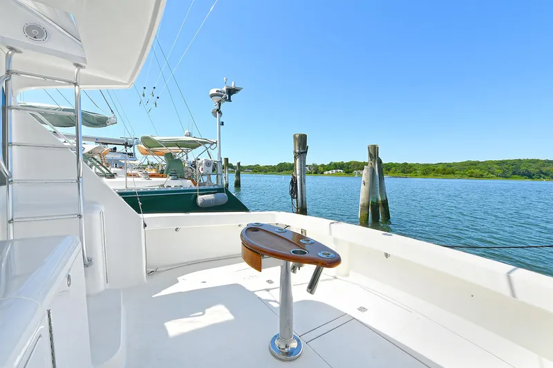 Salty Dog Yacht Photos Pics 2002 Viking 48 Convertible yacht docked by serene waters, featuring a spacious deck.