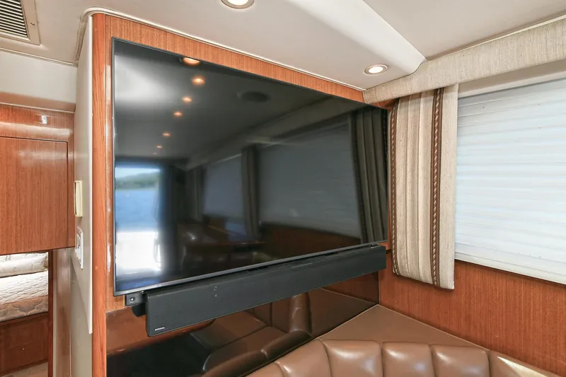 Salty Dog Yacht Photos Pics Flat-screen TV in 2002 Viking 48 Convertible yacht interior with leather seating and wood paneling.