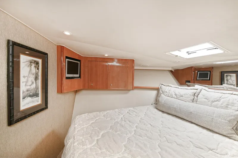 Salty Dog Yacht Photos Pics Luxurious bedroom interior of 2002 Viking 48 Convertible yacht with cozy bedding and wooden cabinets.