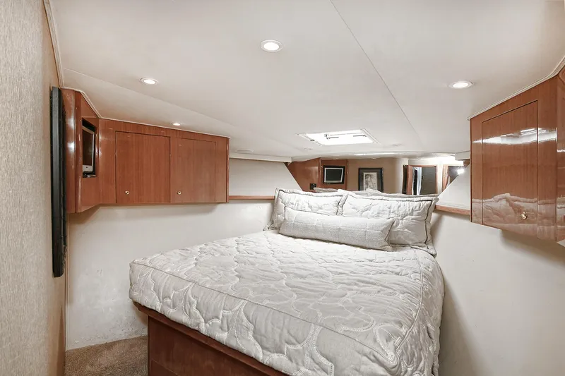 Salty Dog Yacht Photos Pics Luxurious bedroom interior of 2002 Viking 48 Convertible yacht with cozy bedding and wooden cabinets.