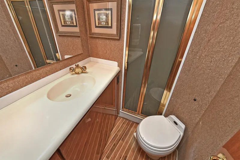 Salty Dog Yacht Photos Pics Luxurious bathroom in 2002 Viking 48 Convertible yacht with gold accents and framed artwork.