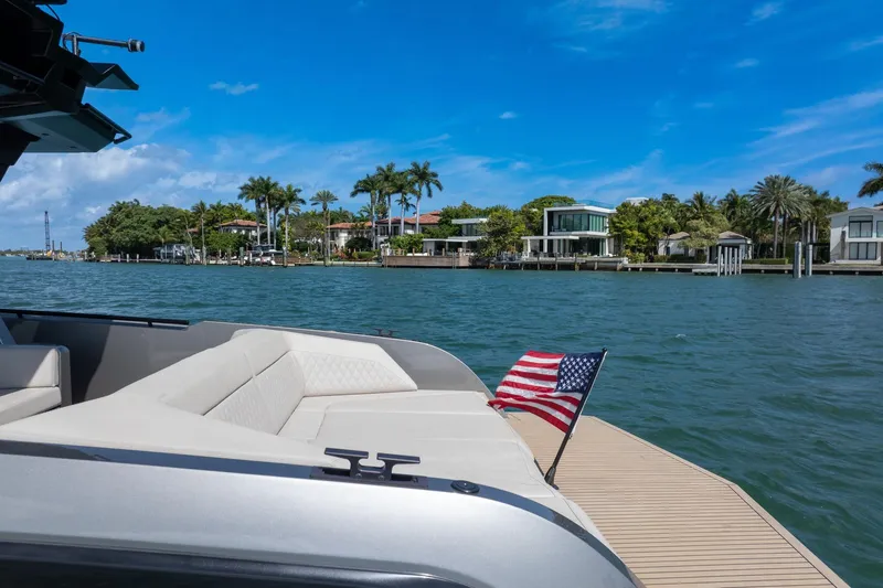  Yacht Photos Pics Luxurious 2022 Vanquish VQ40 yacht cruising near waterfront homes, featuring an American flag.