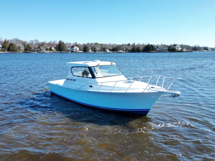  Yacht Photos Pics 2025 Henriques 35 Express Hardtop boat cruising on a calm lake under clear skies.