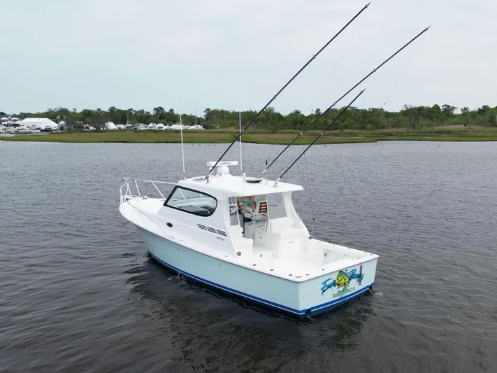  Yacht Photos Pics 2025 Henriques 35 Express Hardtop boat on calm water, featuring fishing rods and sleek design.