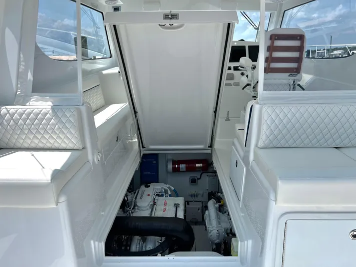  Yacht Photos Pics 2025 Henriques 35 Express Hardtop interior with open engine compartment, white seating, and control panel.