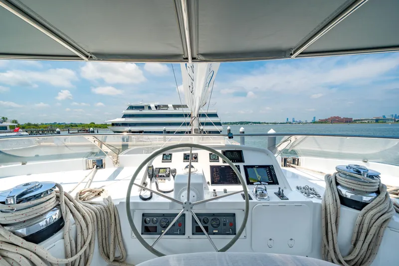 Sur L'eau Yacht Photos Pics Helm of 2008 Privilege 745 yacht with navigation equipment, overlooking calm waters and distant cityscape.