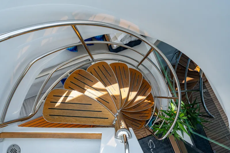 Sur L'eau Yacht Photos Pics Spiral staircase on 2008 Privilege 745 yacht with wooden steps and metal railing.