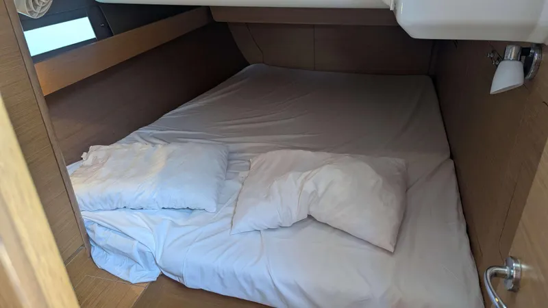 Nevis Yacht Photos Pics Cozy cabin bed inside 2017 Dufour 460 Grand Large yacht, featuring white bedding and wooden interior.