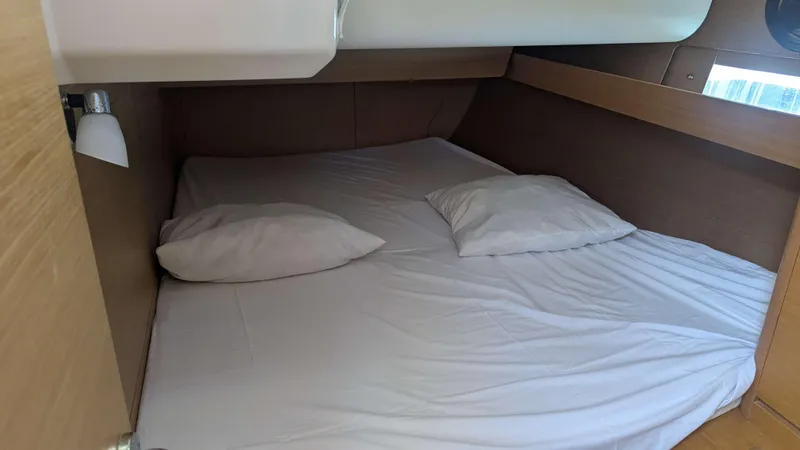 Nevis Yacht Photos Pics Cozy cabin bed in 2017 Dufour 460 Grand Large yacht, featuring white bedding and wooden accents.