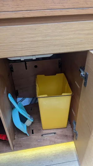 Nevis Yacht Photos Pics Yellow bin and dustpan inside a wooden cabinet on a 2017 Dufour 460 Grand Large yacht.