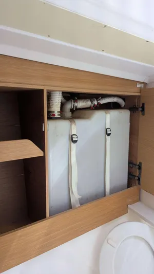 Nevis Yacht Photos Pics Cabinet interior of 2017 Dufour 460 Grand Large yacht, showing plumbing and storage.