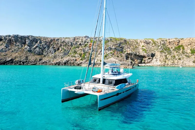 Sunnyacht Yacht Photos Pics 2008 Sunreef 62 catamaran anchored in turquoise waters near rocky coastline.