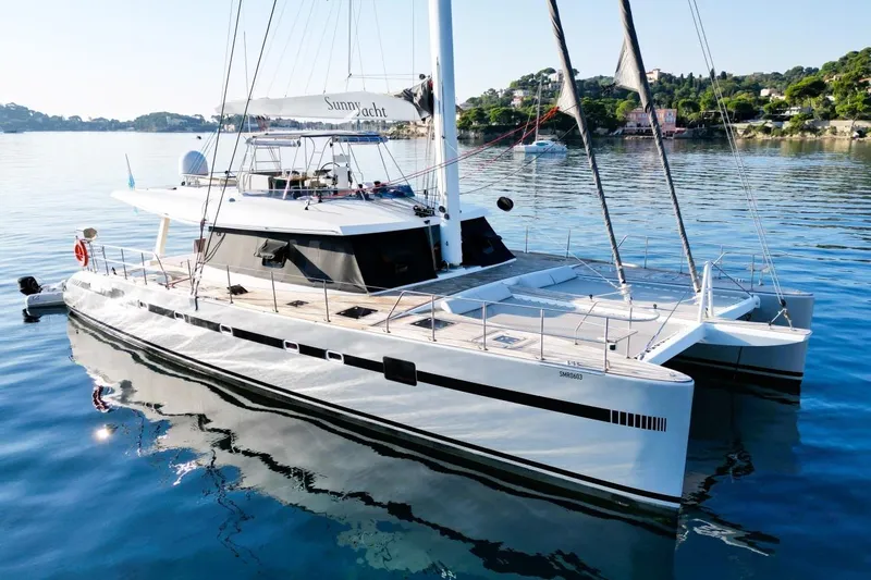 Sunnyacht Yacht Photos Pics Luxury 2008 Sunreef 62 catamaran yacht on calm waters, scenic coastal backdrop.