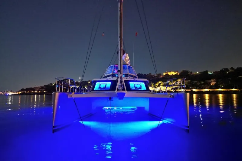 Sunnyacht Yacht Photos Pics 2008 Sunreef 62 catamaran with blue underwater lights, docked at night.