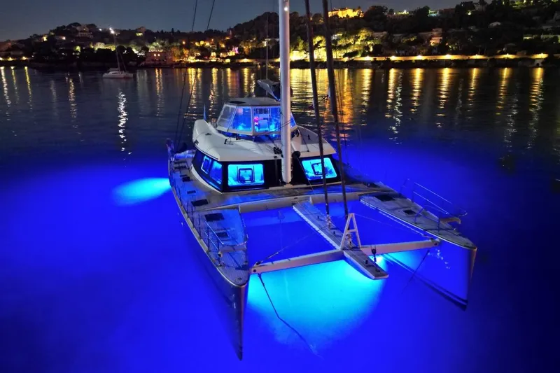 Sunnyacht Yacht Photos Pics Luxurious 2008 Sunreef 62 catamaran with blue underwater lights in a serene night harbor.