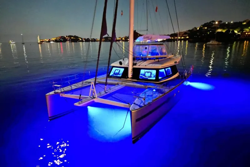 Sunnyacht Yacht Photos Pics Luxurious 2008 Sunreef 62 catamaran illuminated with blue lights on calm water at night.
