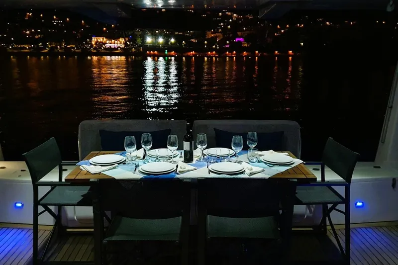 Sunnyacht Yacht Photos Pics Elegant dining setup on 2008 Sunreef 62 yacht, overlooking illuminated waterfront at night.