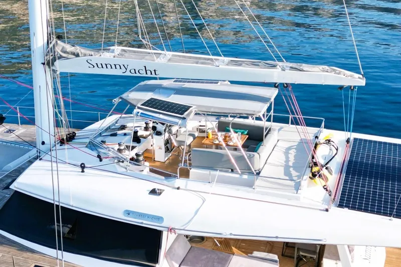 Sunnyacht Yacht Photos Pics Sunreef 62 yacht from 2008 with solar panels, docked on calm blue water.