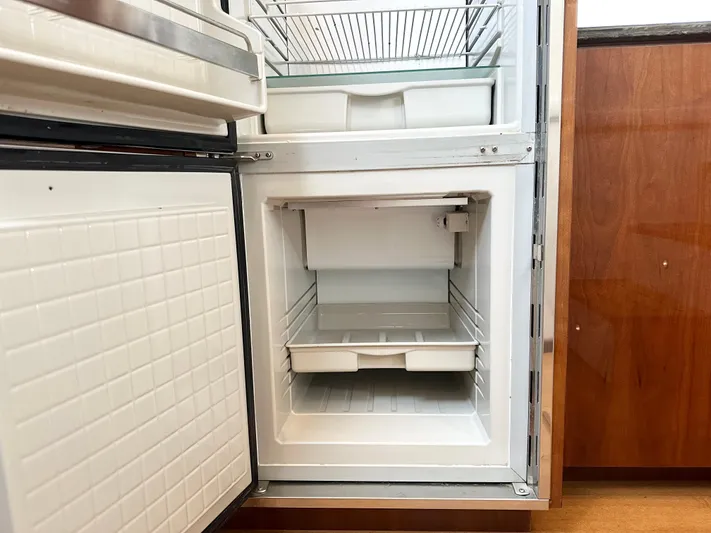  Yacht Photos Pics Open refrigerator inside a 2012 Sea Ray 450 Sedan Bridge yacht, showing empty shelves and drawers.
