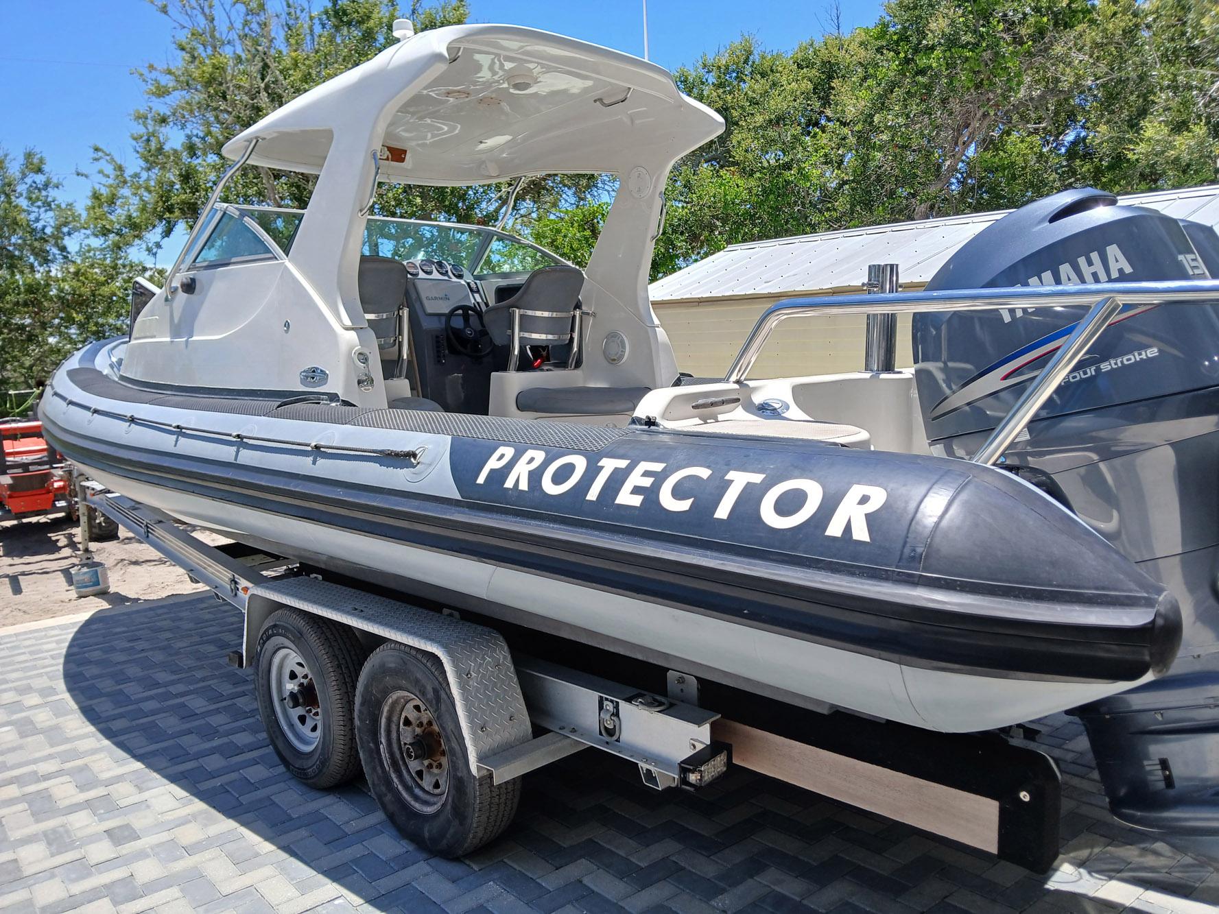 2002 Protector 28 Targa boat on trailer, featuring Yamaha outboard motor, parked outdoors.