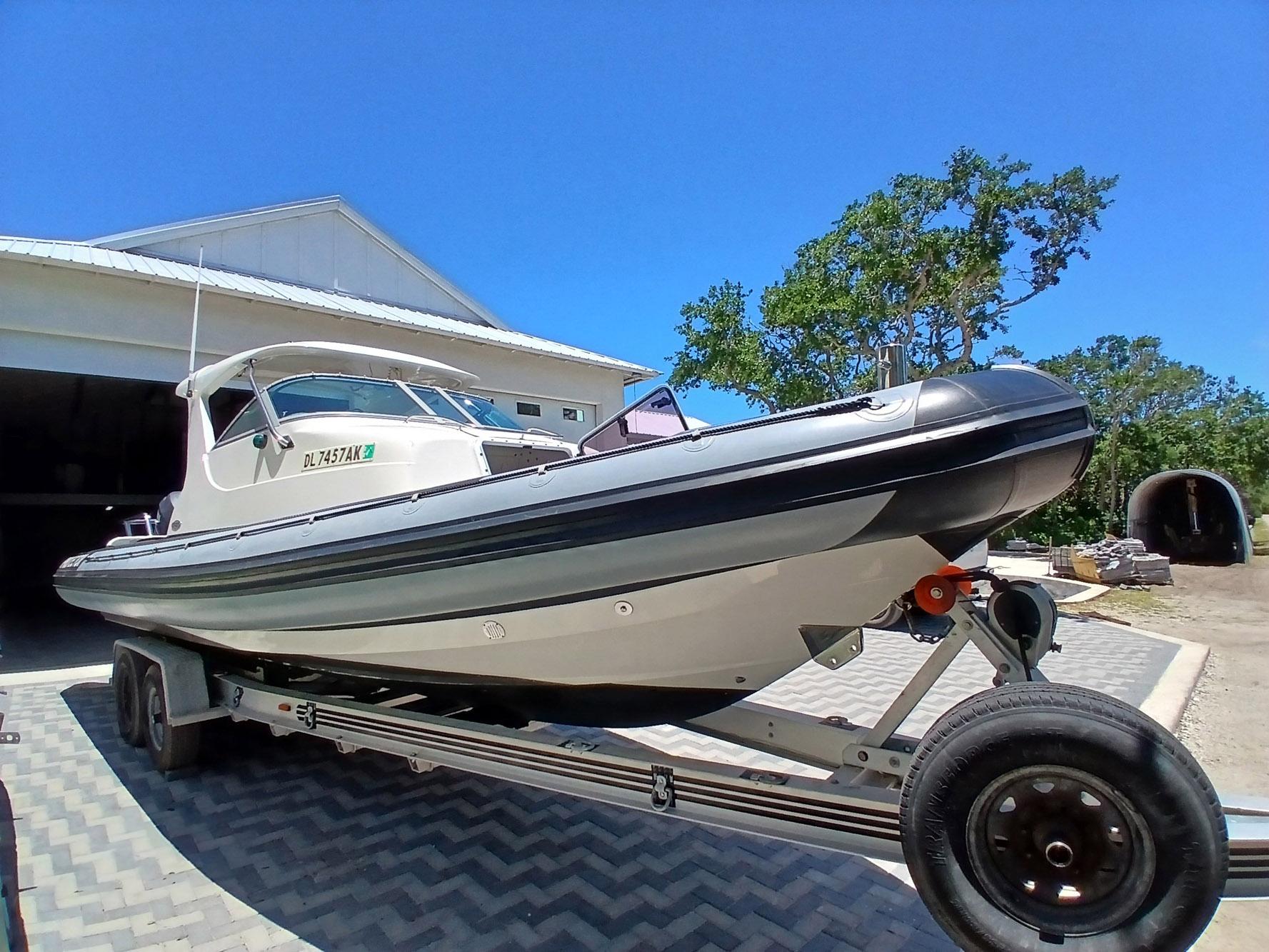 2002 Protector 28 Targa boat on trailer, parked outdoors under clear blue sky.