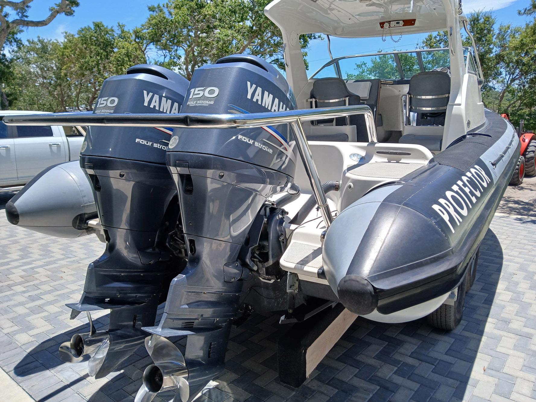 2002 Protector 28 Targa boat with twin Yamaha 150 four-stroke engines, parked on a paved surface.