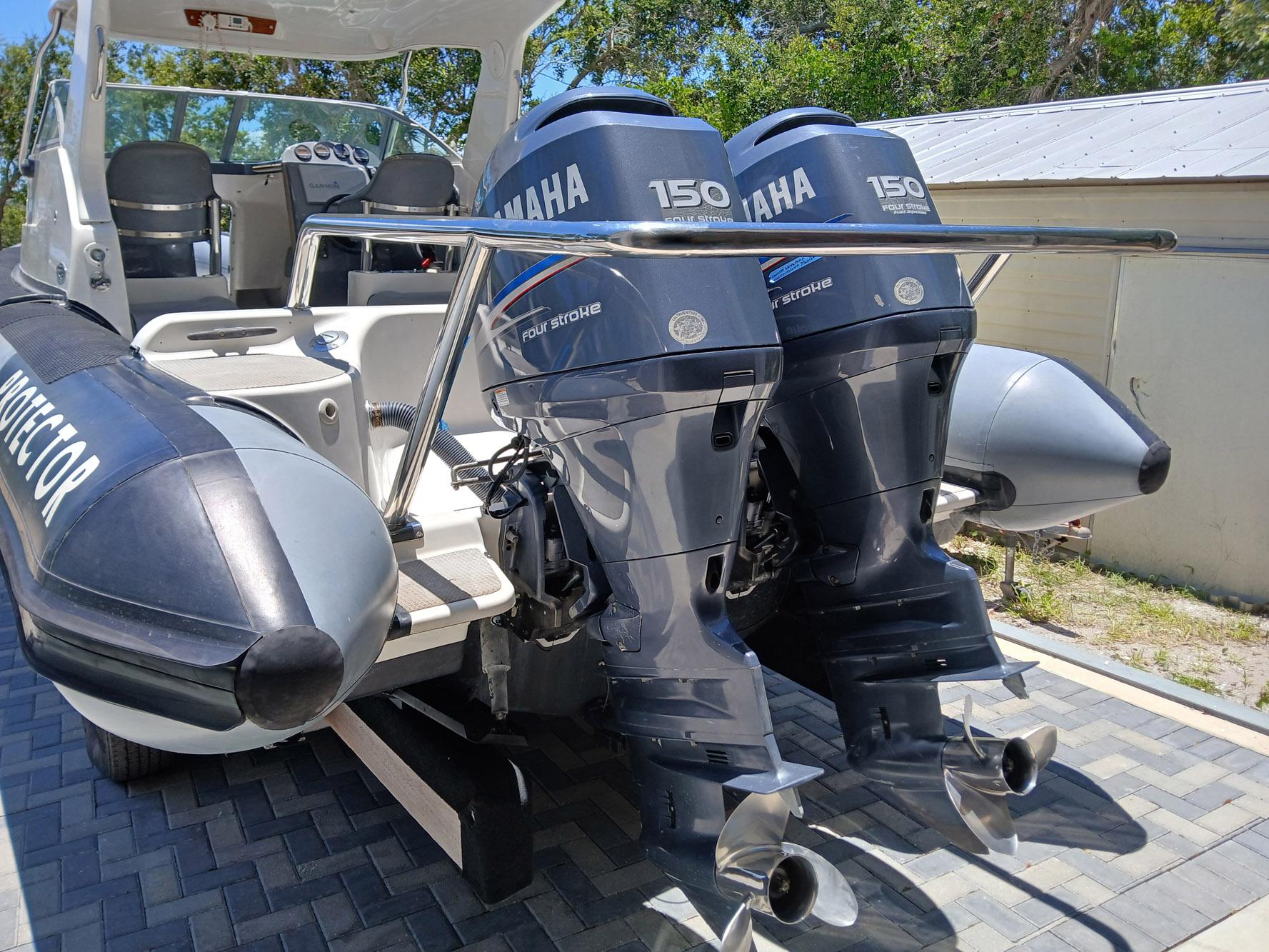 2002 Protector 28 Targa boat with dual Yamaha 150 four-stroke engines, docked outdoors.