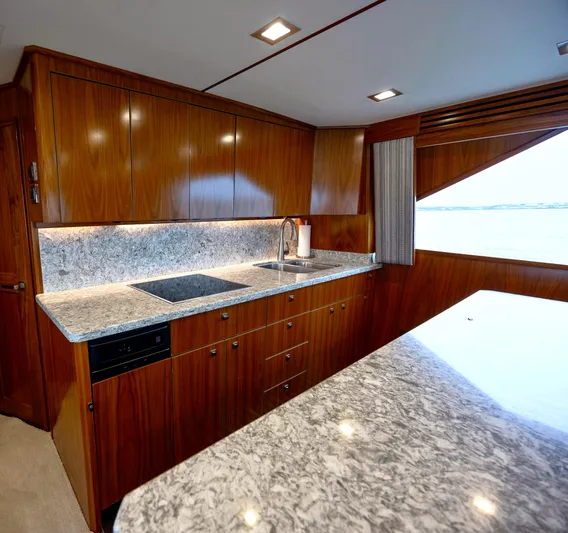 Slow Your Roll Yacht Photos Pics Luxurious kitchen interior of 2019 Viking 68 Convertible yacht with wood cabinetry and marble countertops.