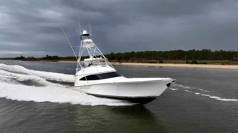 Slow Your Roll Yacht Photos Pics 2019 Viking 68 Convertible yacht cruising on a calm waterway under cloudy skies.